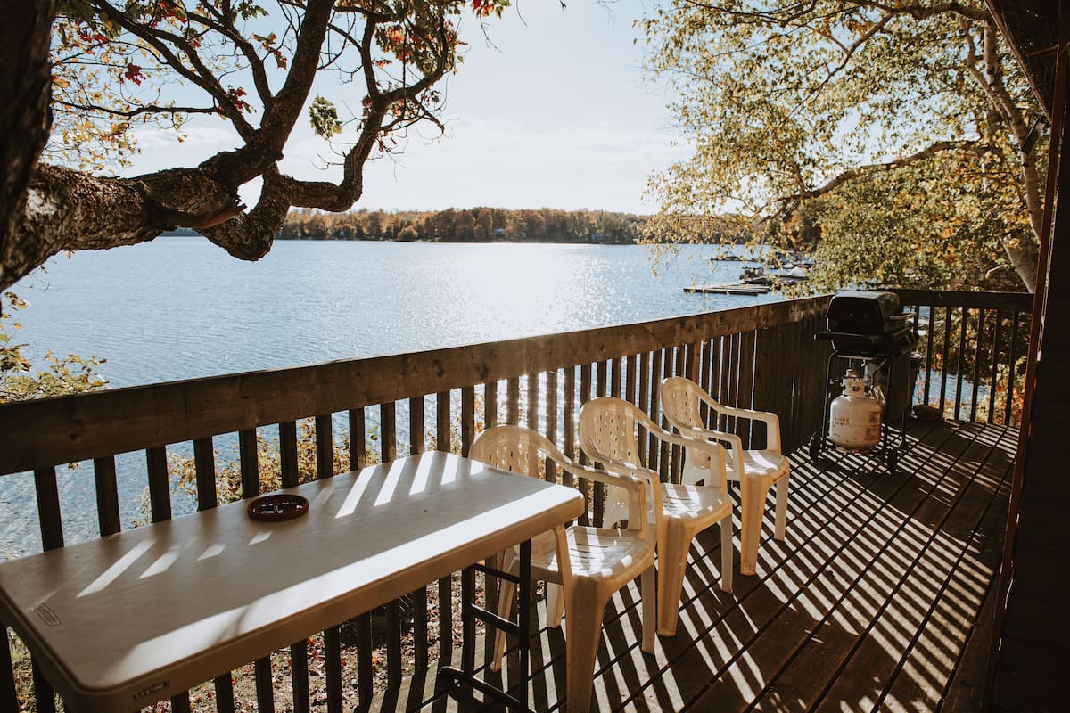 A wooden deck with a table and chairs overlooking a lake.