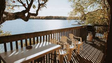 A wooden deck with a table and chairs overlooking a lake.