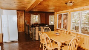 A wooden interior with a dining table and chairs, a sofa, and a fireplace. - Lang Lake Resort (Unorganized North Sudbury)
