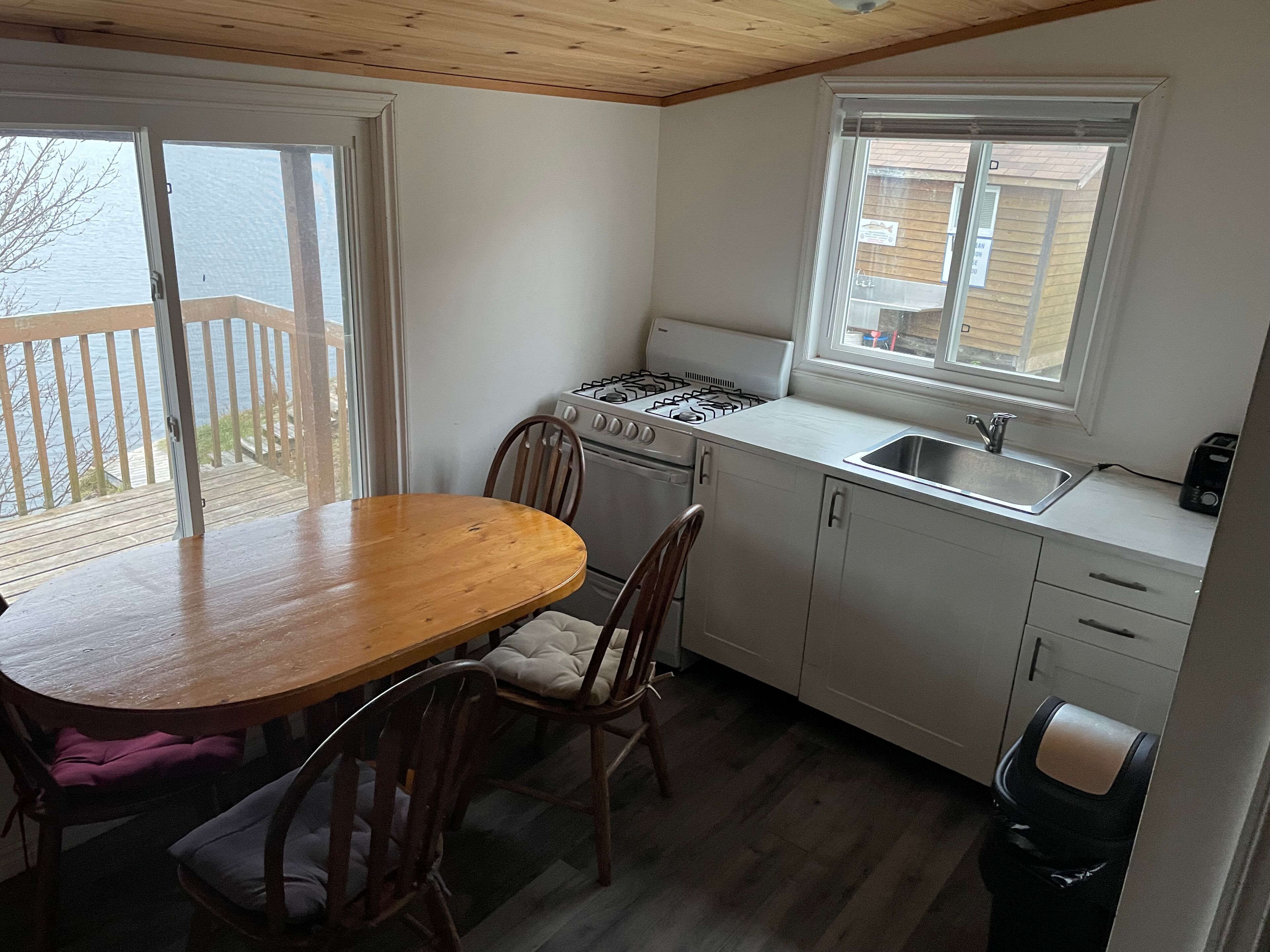 Une cuisine de taille réduite avec une table en bois, des chaises, une cuisinière et une fenêtre.