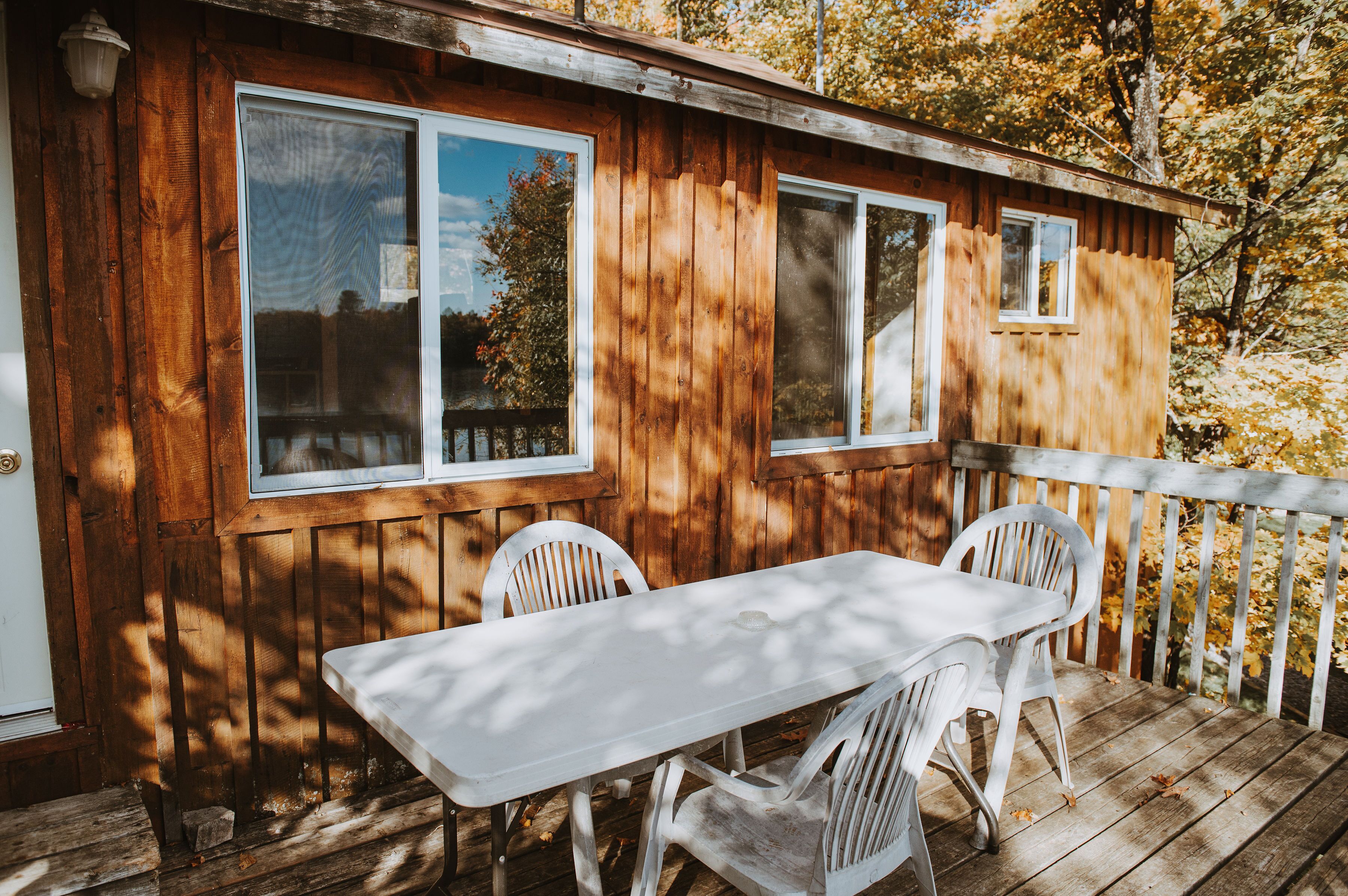 Een houten chalet met terras, tafel en twee stoelen.