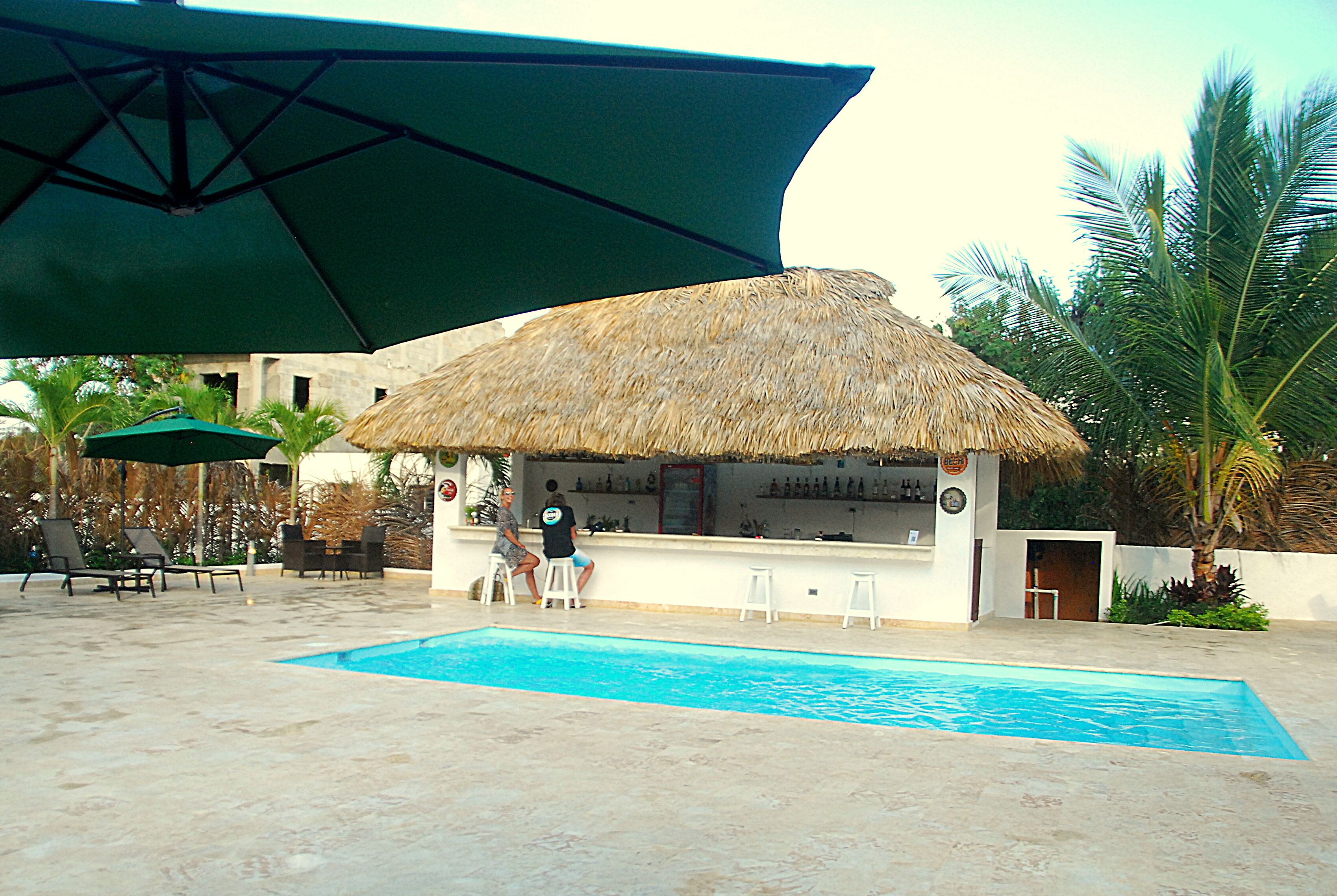 Un espace piscine doté d’un bar, de chaises longues et de parasols.