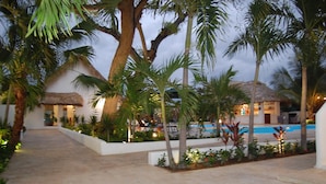 A resort with a pool, palm trees, and thatched-roof huts. - Hotel Playa Catalina (La Romana)