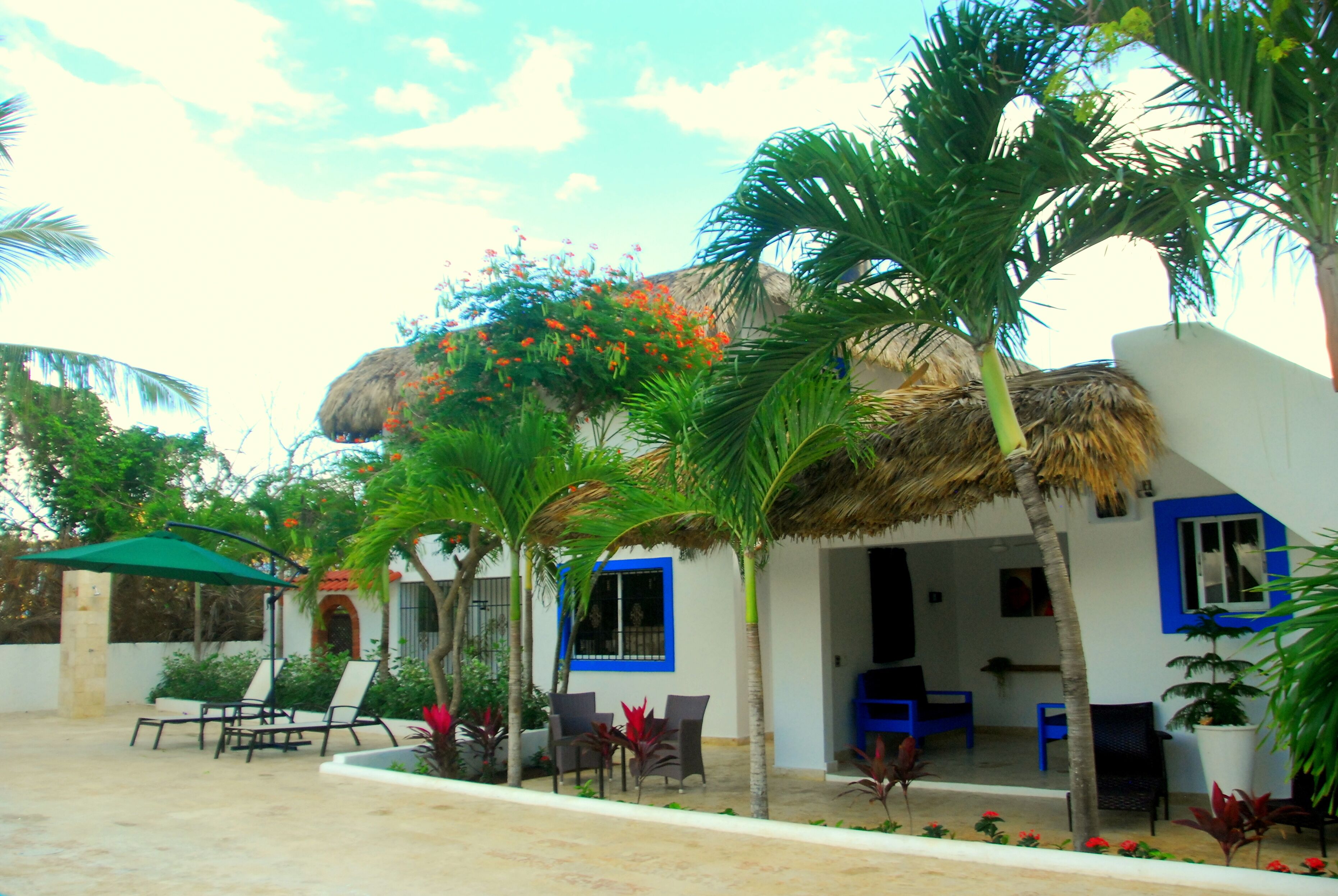 A resort with a thatched-roof structure, outdoor seating, and palm trees.