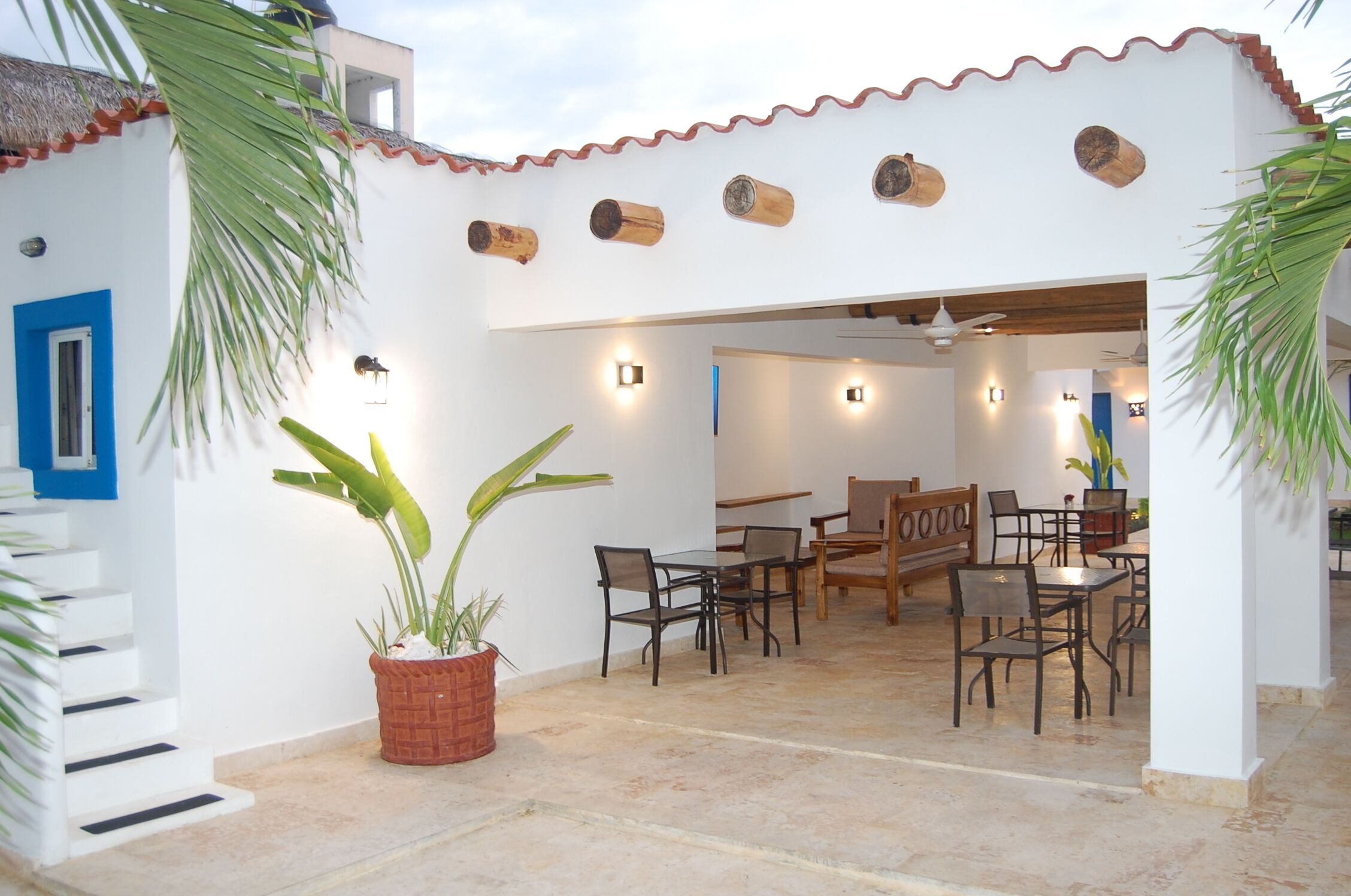 A patio area with a dining table and chairs, surrounded by white walls and a tiled floor.
