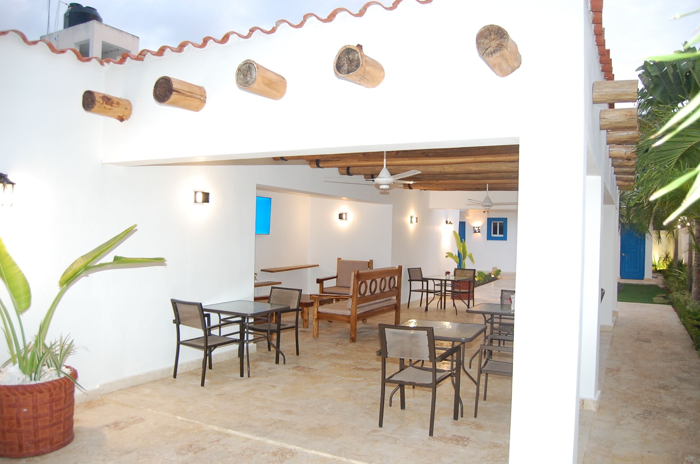 An outdoor patio area with wooden furniture, a ceiling fan, and a blue door in the background.