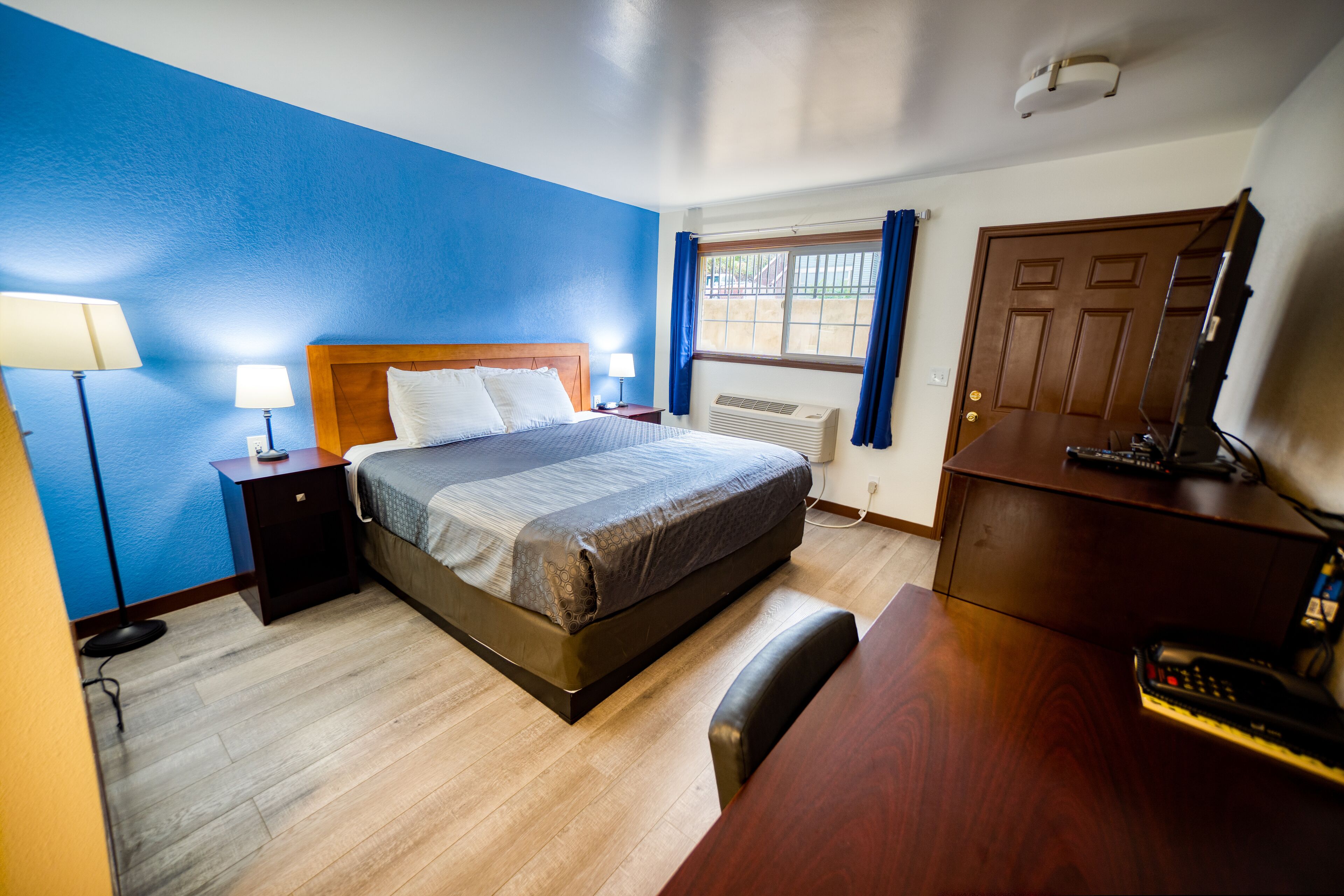 A hotel room with a bed, bedside tables, a desk, and a chair.
