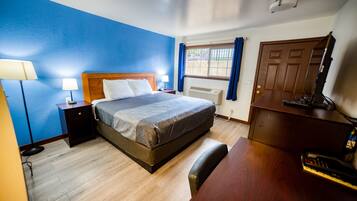 A hotel room with a bed, bedside tables, a desk, and a chair.