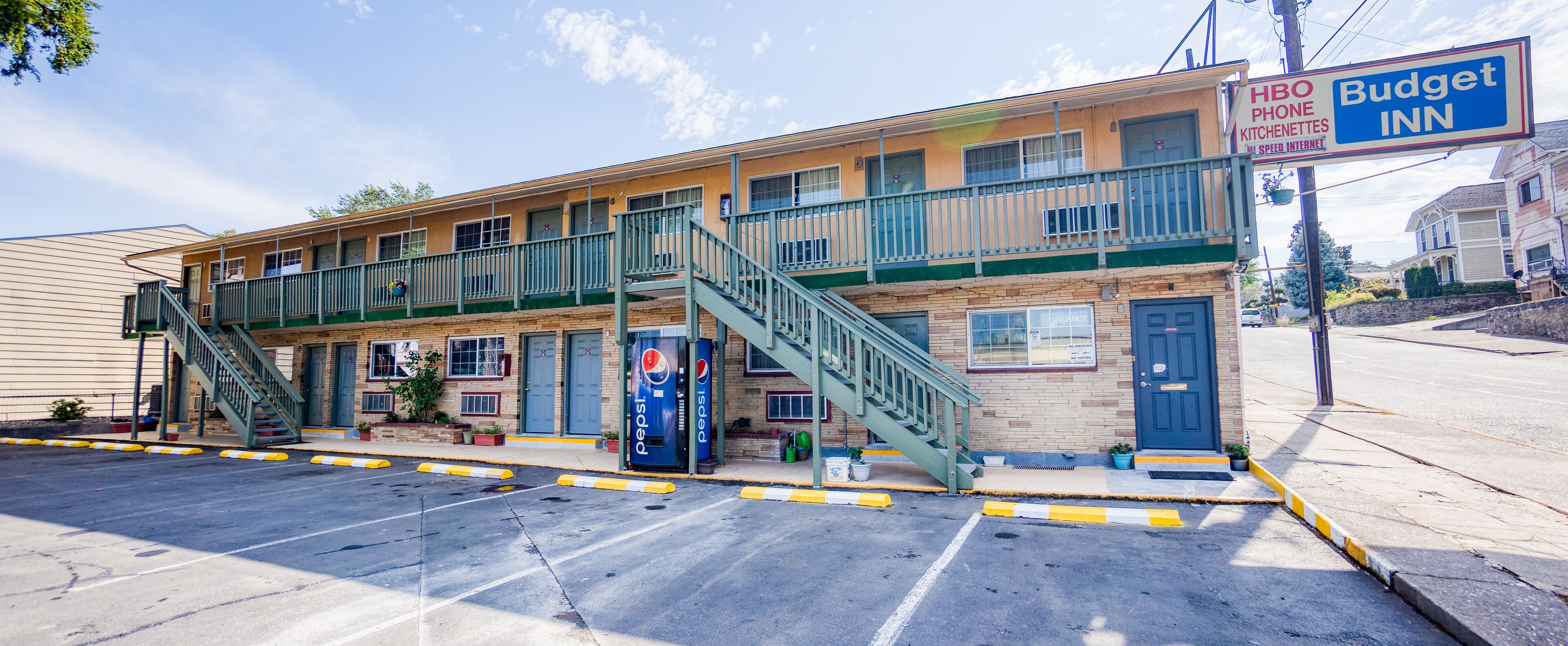 A two-story motel with a balcony, a Pepsi vending machine, and a sign for HBO and Budget Inn.
