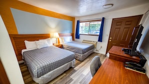 A hotel room with two beds, a desk, a chair, a television, and a window with curtains. - Budget Inn Motel (The Dalles)