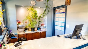 A reception desk with a computer, a clock, and a calendar on the wall. - Budget Inn Motel (The Dalles)