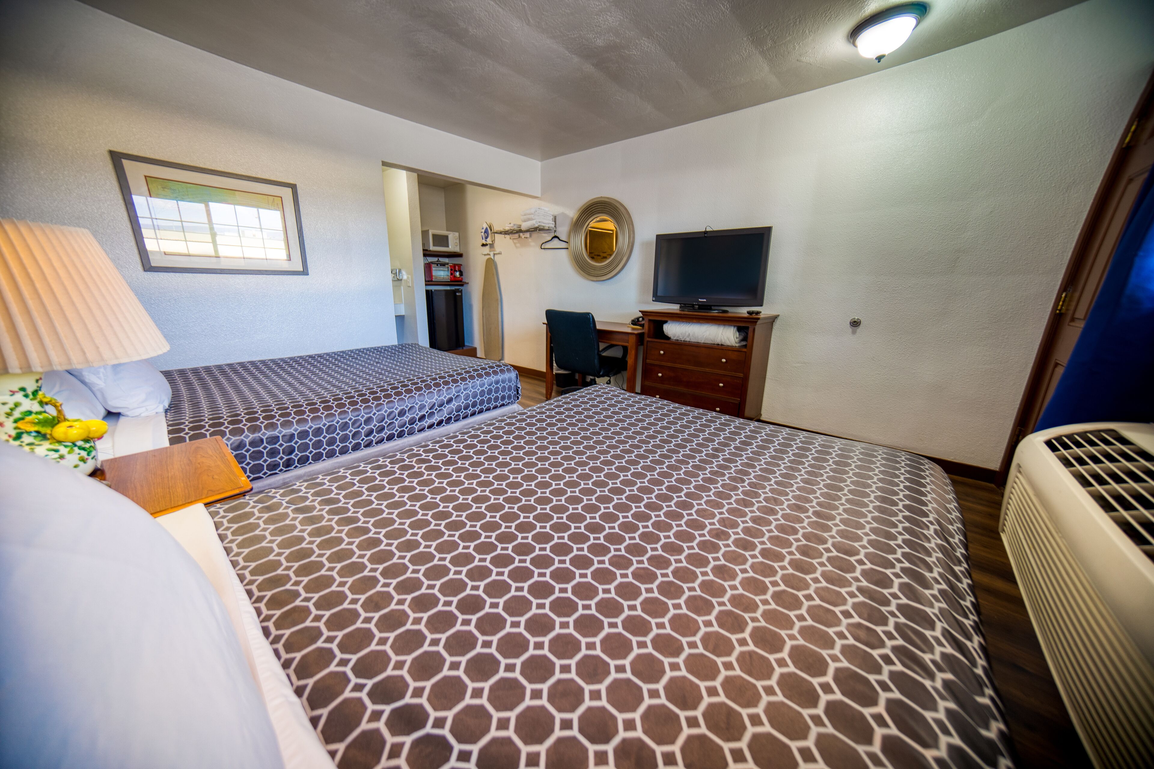 Une chambre d’hôtel avec deux lits, un bureau, une télévision, un four à micro-ondes et un radiateur.