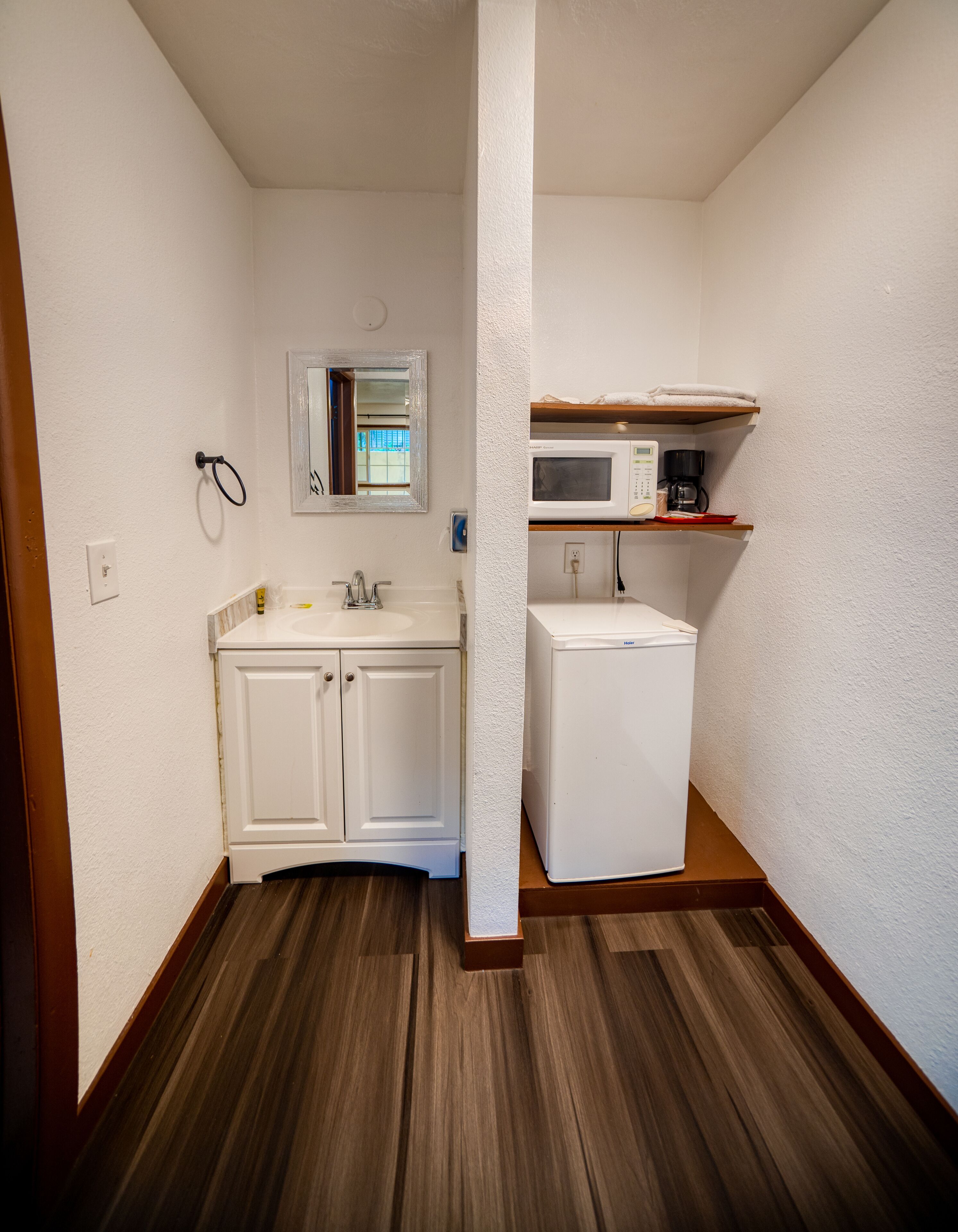 A small kitchenette with a microwave, a sink, and a refrigerator.