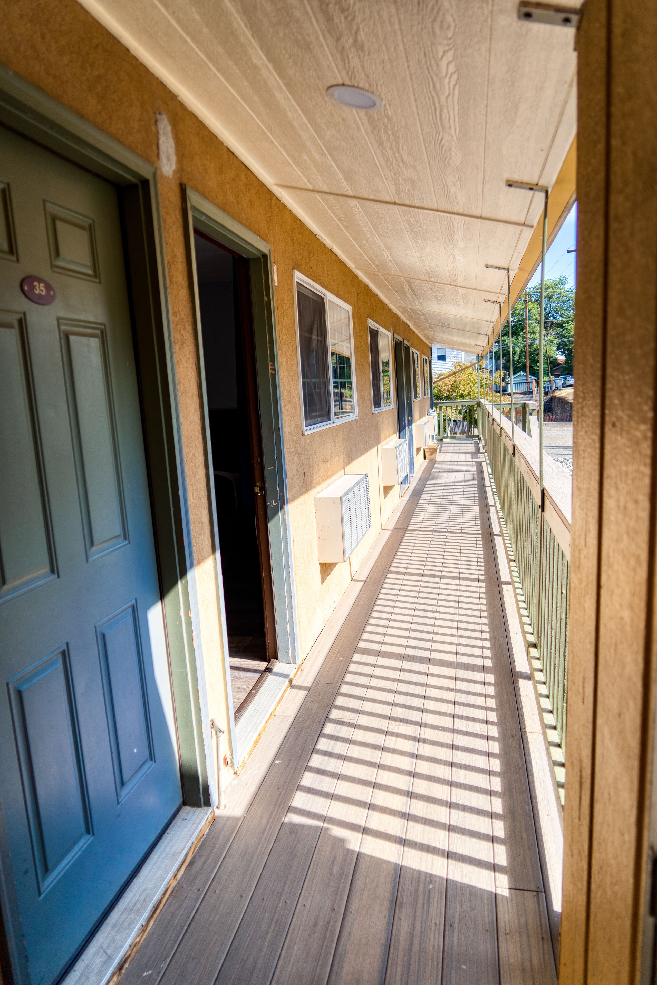 A corridor with a wooden floor and a blue door on the left.