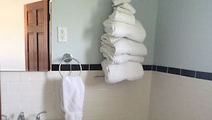 Casa de banho com lavatório, sanita e uma pilha de toalhas.