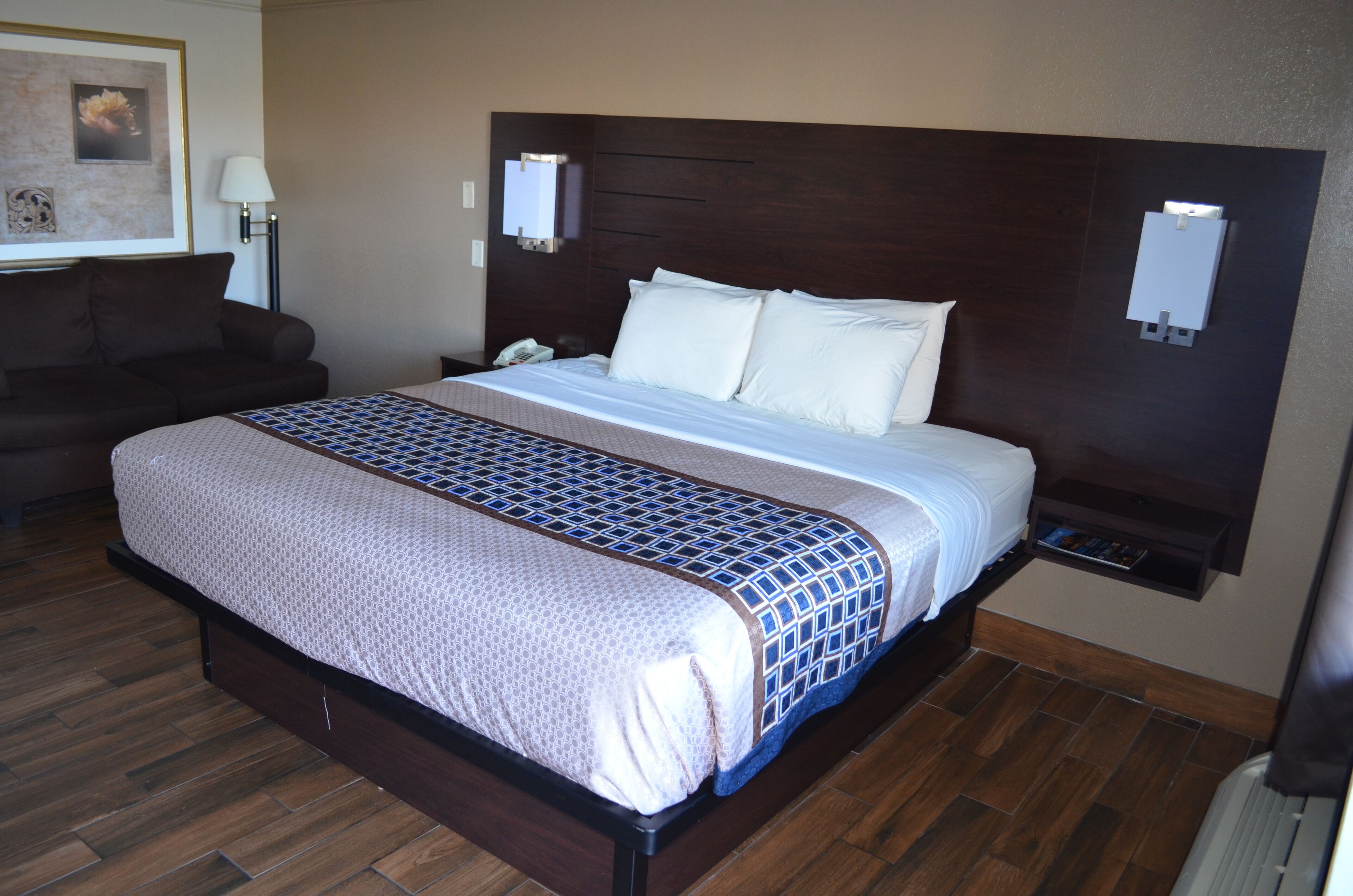 A neatly made bed with a patterned bedspread, a dark headboard, and bedside lamps.
