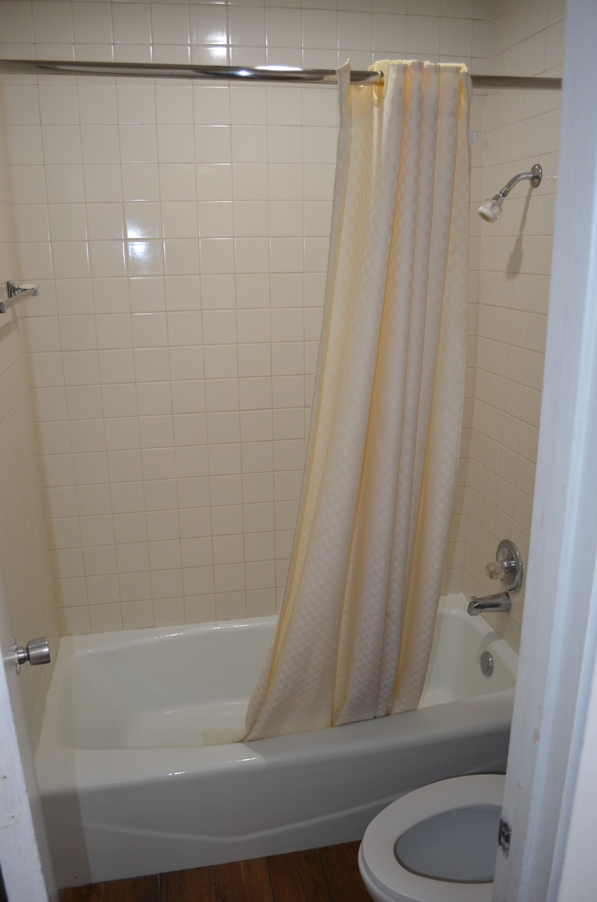 A bathroom with a bathtub, toilet, and a shower curtain.