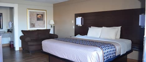 Une chambre d’hôtel avec un grand lit, un canapé, une petite table et un tableau encadré au mur.