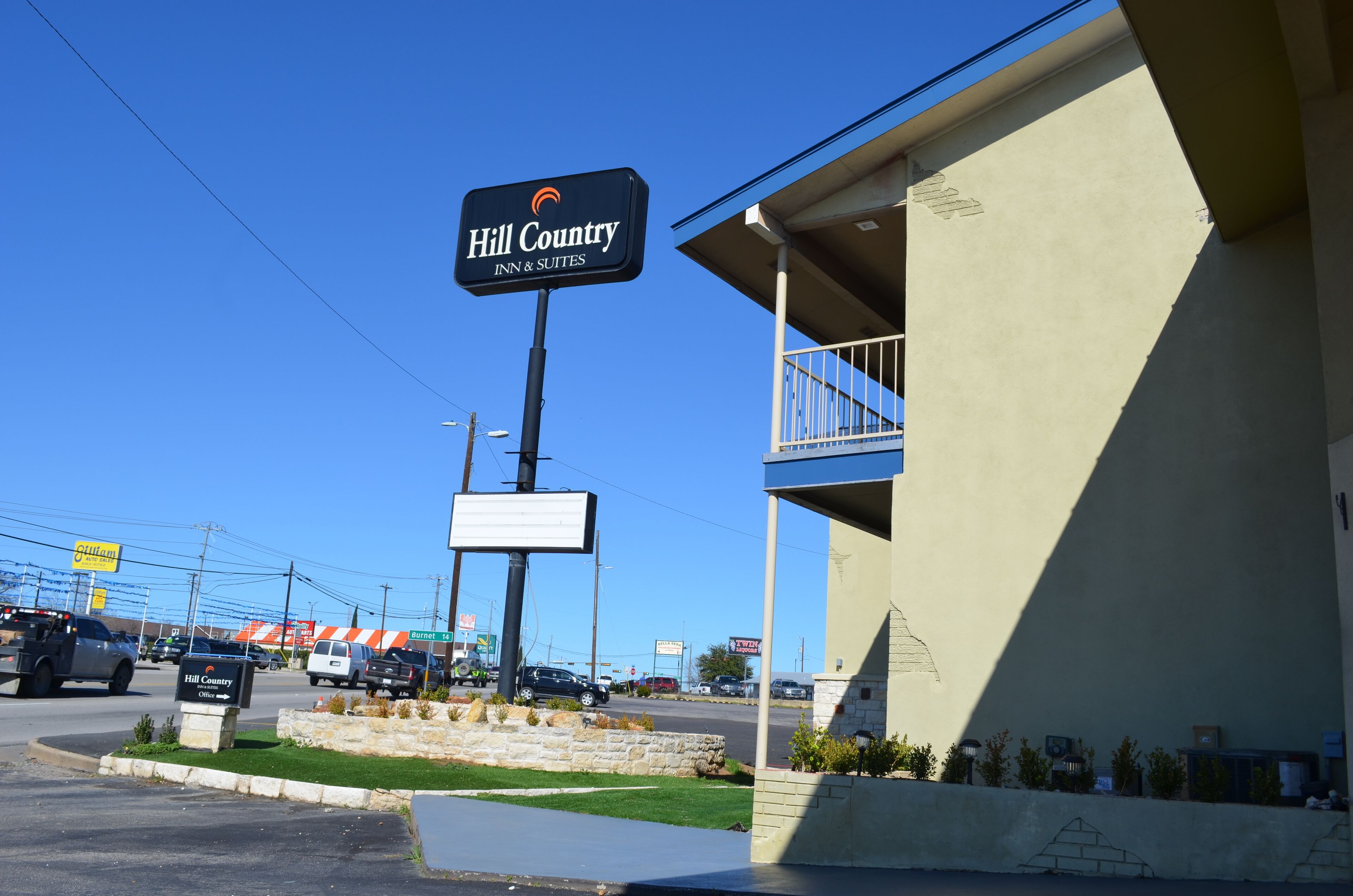 A Hill Country Inn & Suites sign, a parking lot, and a building with a balcony.