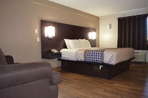 A hotel room with a large bed, a bedside table with a phone, and a chair. - Hill Country Inn Marble Falls (Marble Falls)