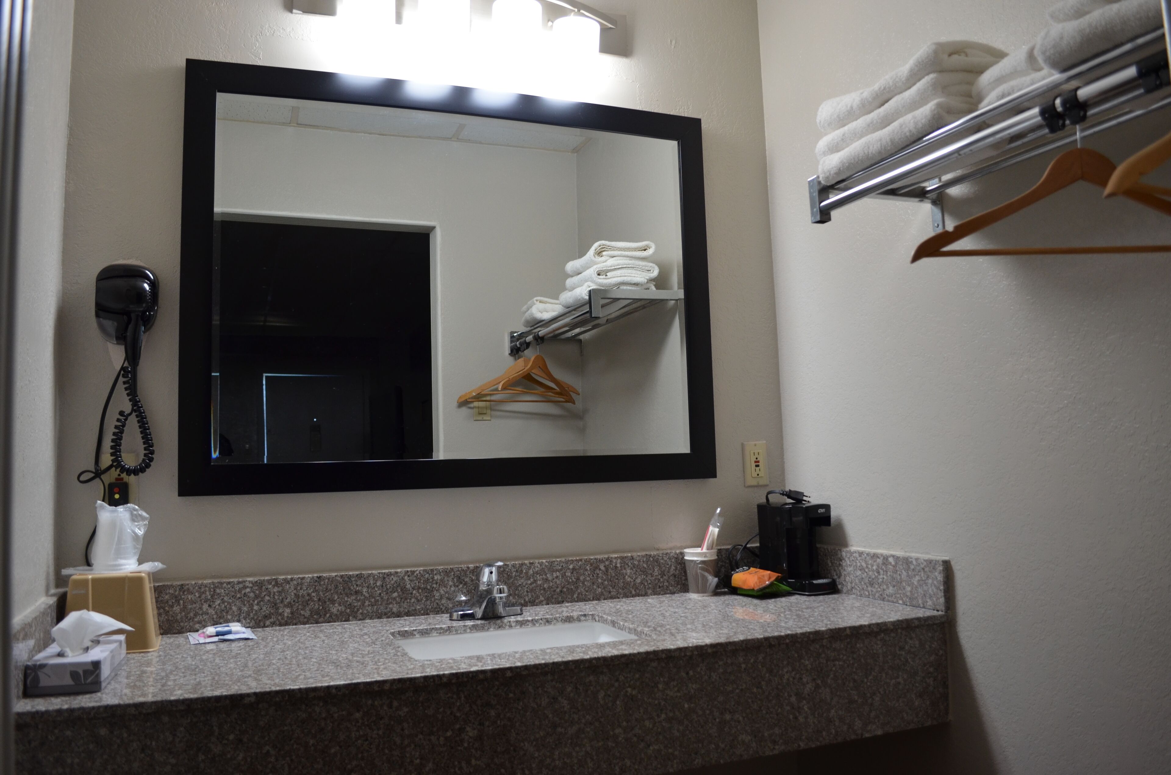 A bathroom with a sink, mirror, towel rack, and a telephone.