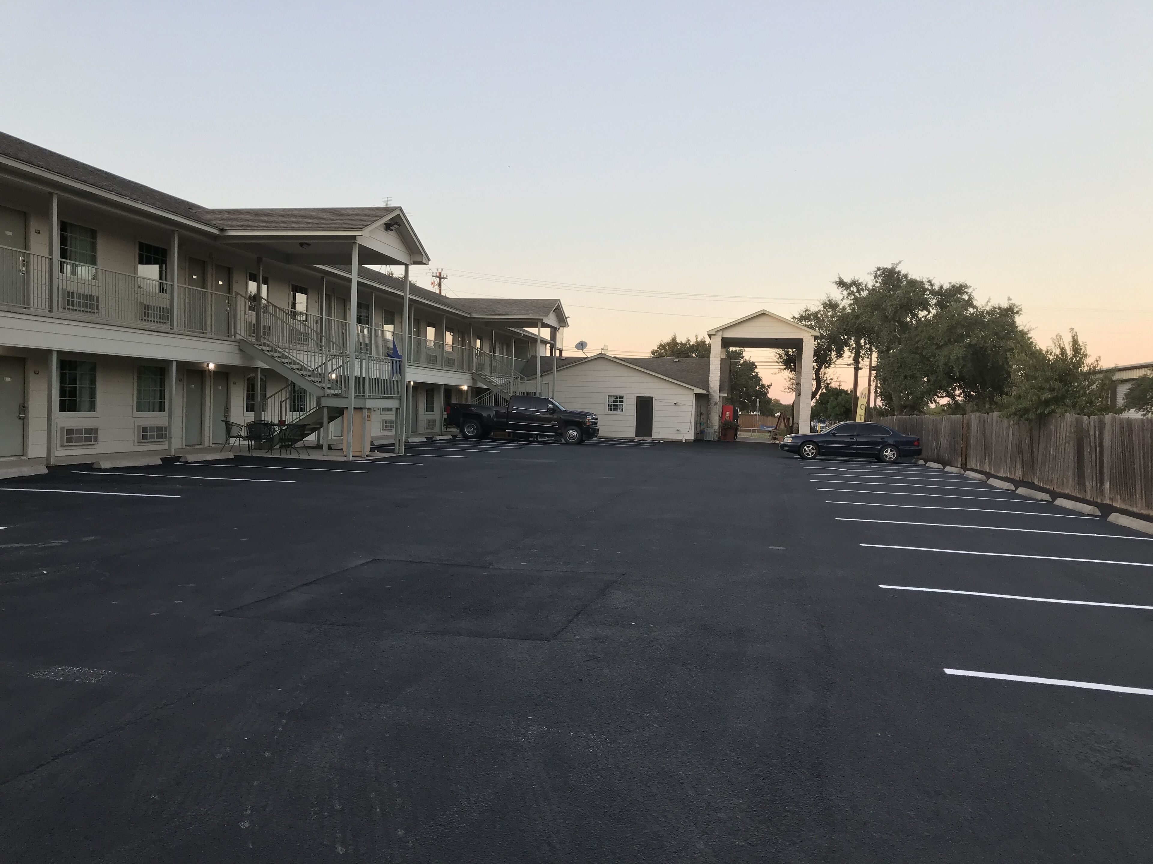 A motel with multiple floors, a covered parking area, and a small building in the center.