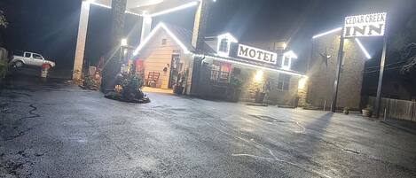 Un motel con un llamativo letrero que dice 'Motel', una pequeña oficina y un estacionamiento.