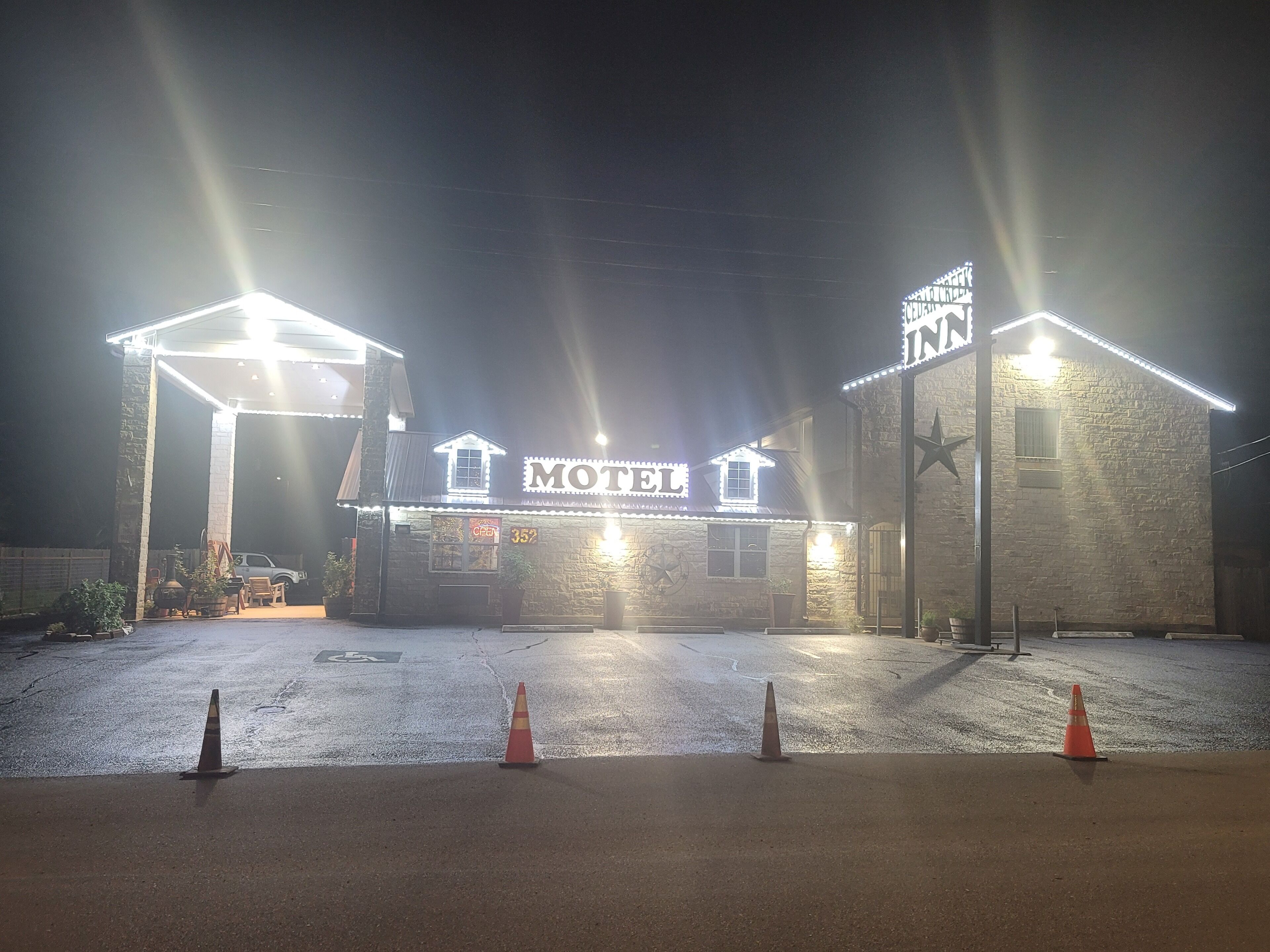 A motel with a sign that reads "MOTEL" and a star symbol. There are orange traffic cones in the foreground.