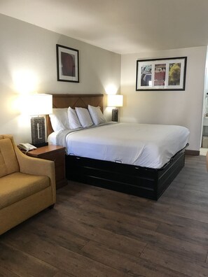 A neatly arranged hotel room with a bed, two bedside lamps, a chair, and a small table with a telephone. - Cedar Creek Inn (Bertram)
