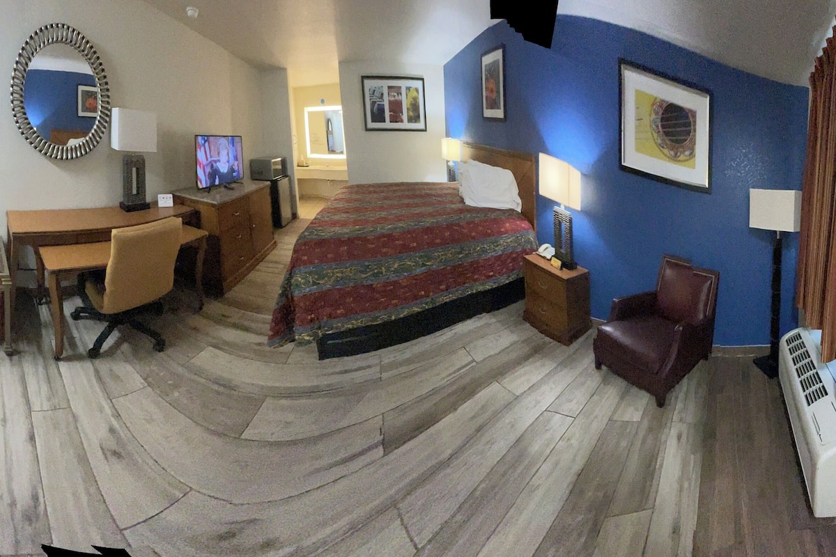 Une chambre d’hôtel avec un lit, un bureau, une chaise et une petite table.