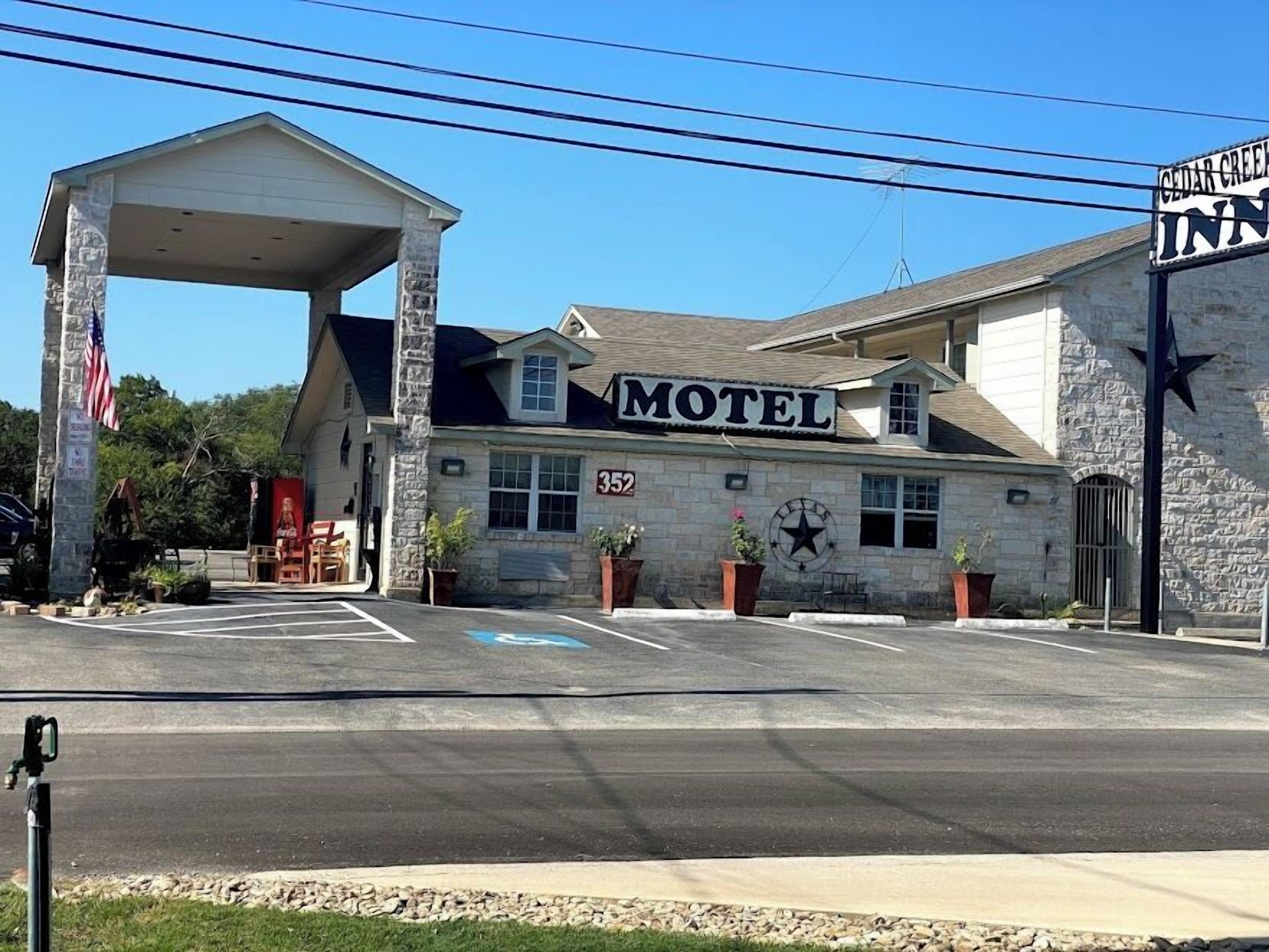 Um motel com uma placa grande, entrada coberta e fachada de pedra.