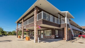 A two-story building with a balcony, a sign reading "CARNEL INN," and flower baskets. - Carmel Inn (Prince George)