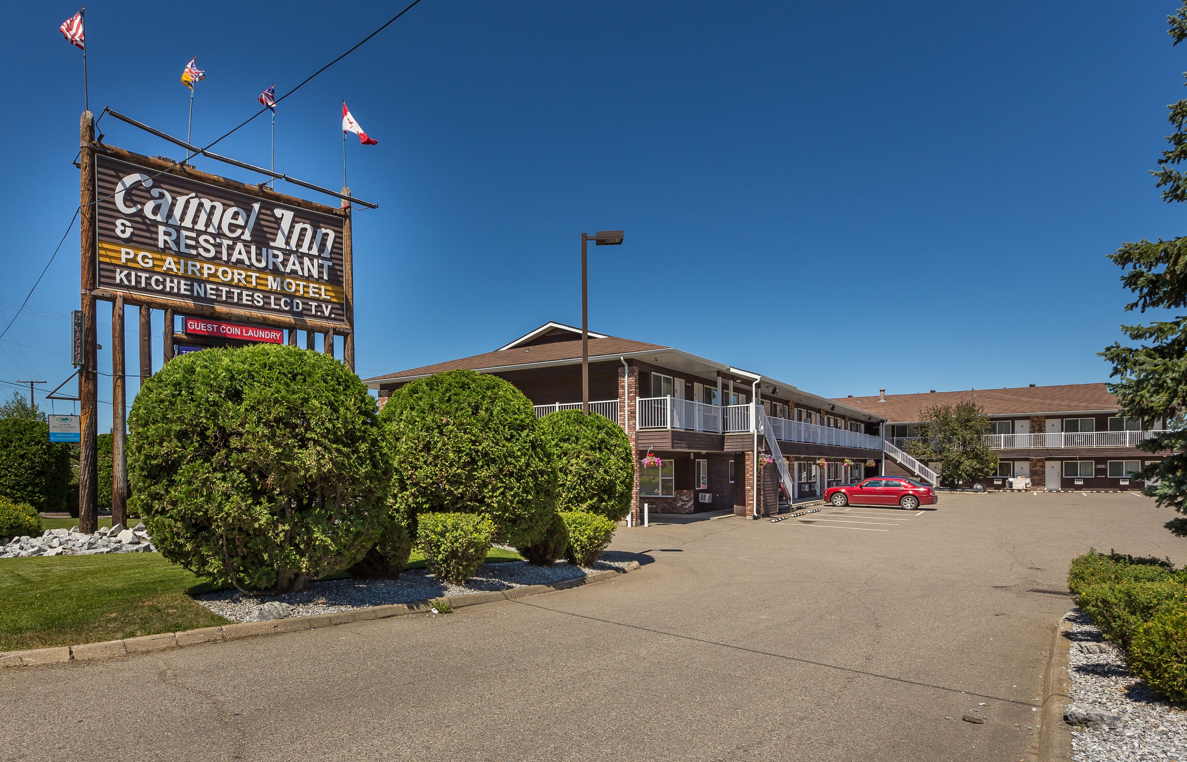 A Camel Inn & Restaurant with a signboard, a red car parked in front, and a clear blue sky.