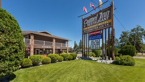 A building with a sign for Carmel Inn & Restaurant Motel, featuring amenities like guest coin laundry, truck and RV parking, and a fitness room. - Carmel Inn (Prince George)
