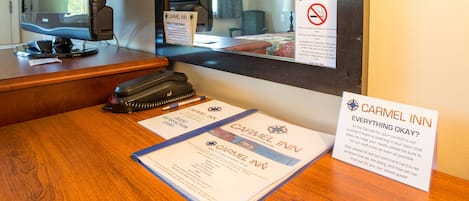 A hotel reception desk with a computer, a sign reading "CARMEL INN," a guest card, and a "CARMEL INN EVERYTHING OKAY?" sign.
