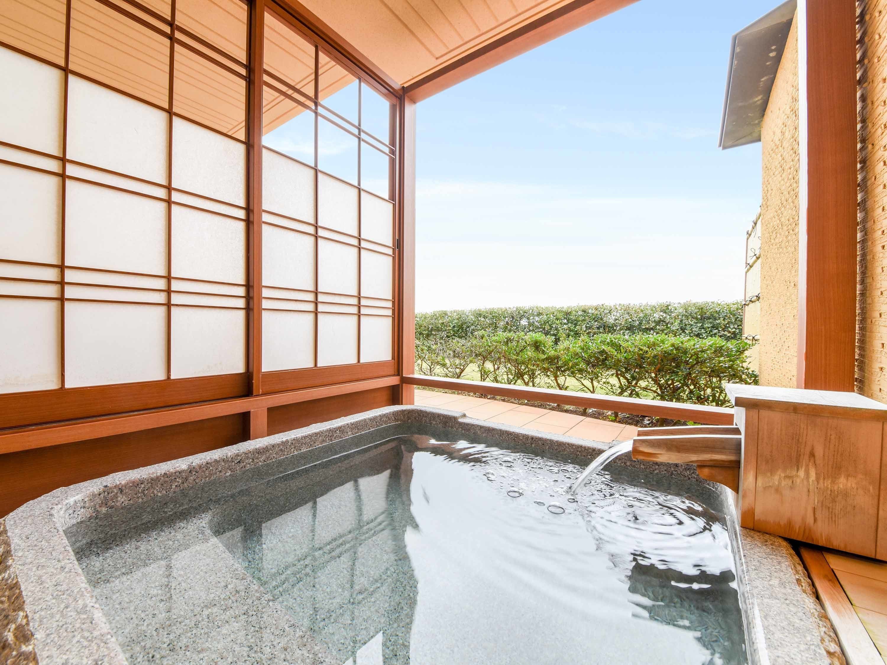 Un jacuzzi con vistas a un jardín y una habitación japonesa tradicional con puertas correderas.