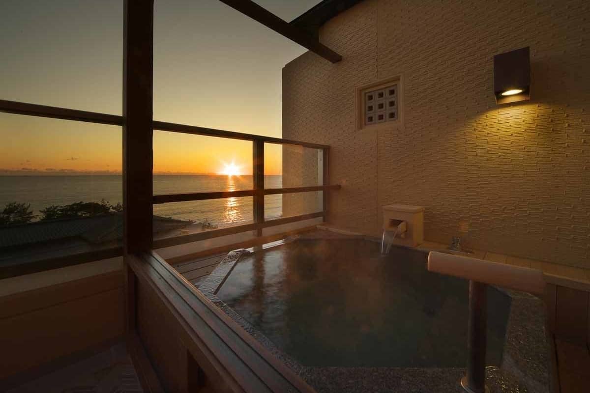 A hot tub with a view of the sunset over the ocean.