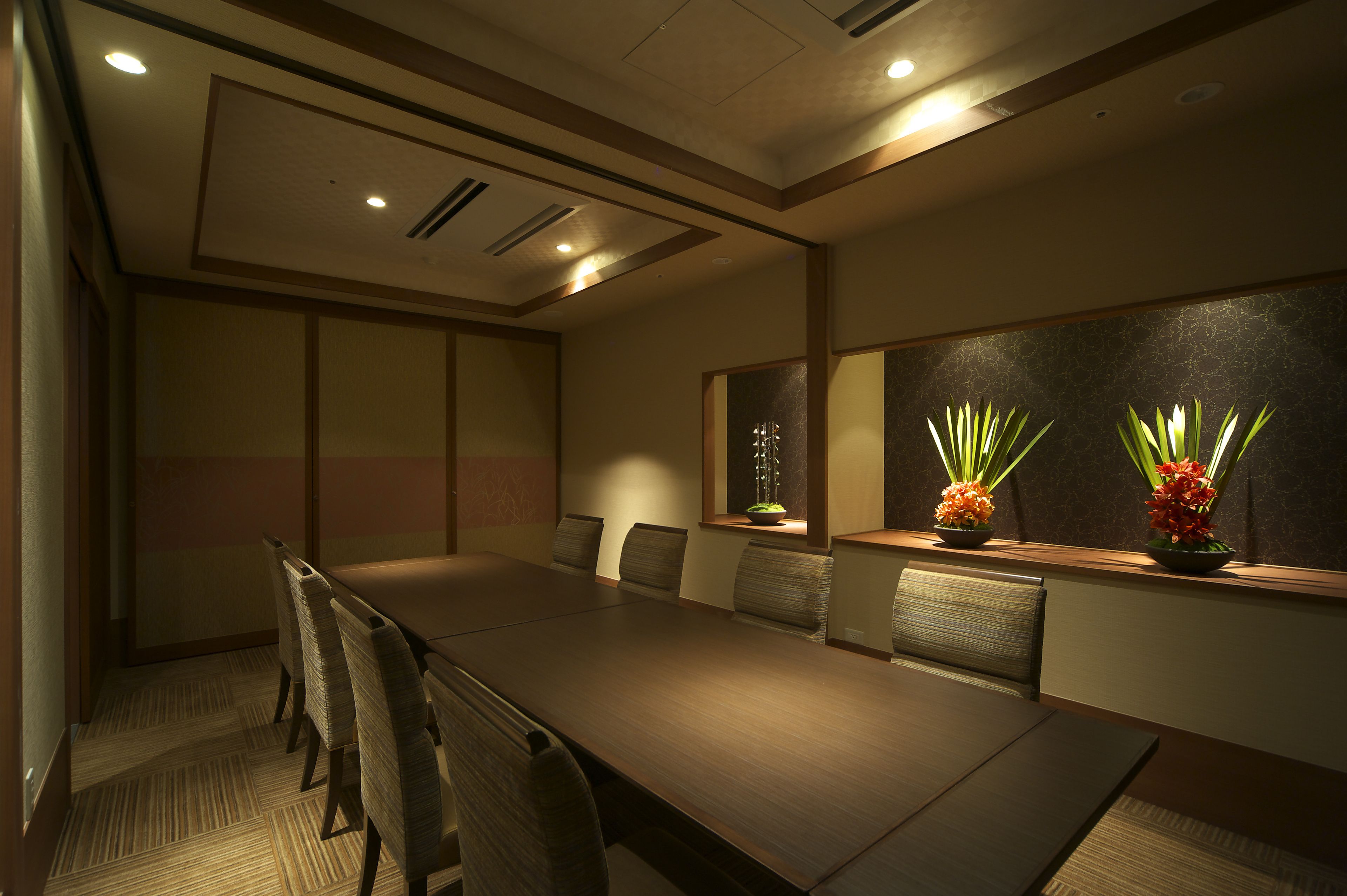 A conference room with a long table, several chairs, and decorative plants.