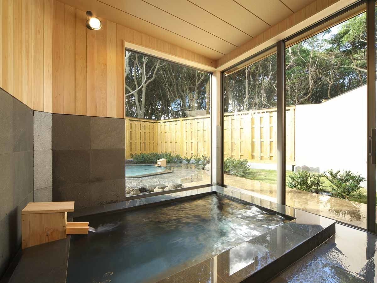 A modern spa area with a hot tub, wooden panel walls, and large windows offering a view of the outdoors.
