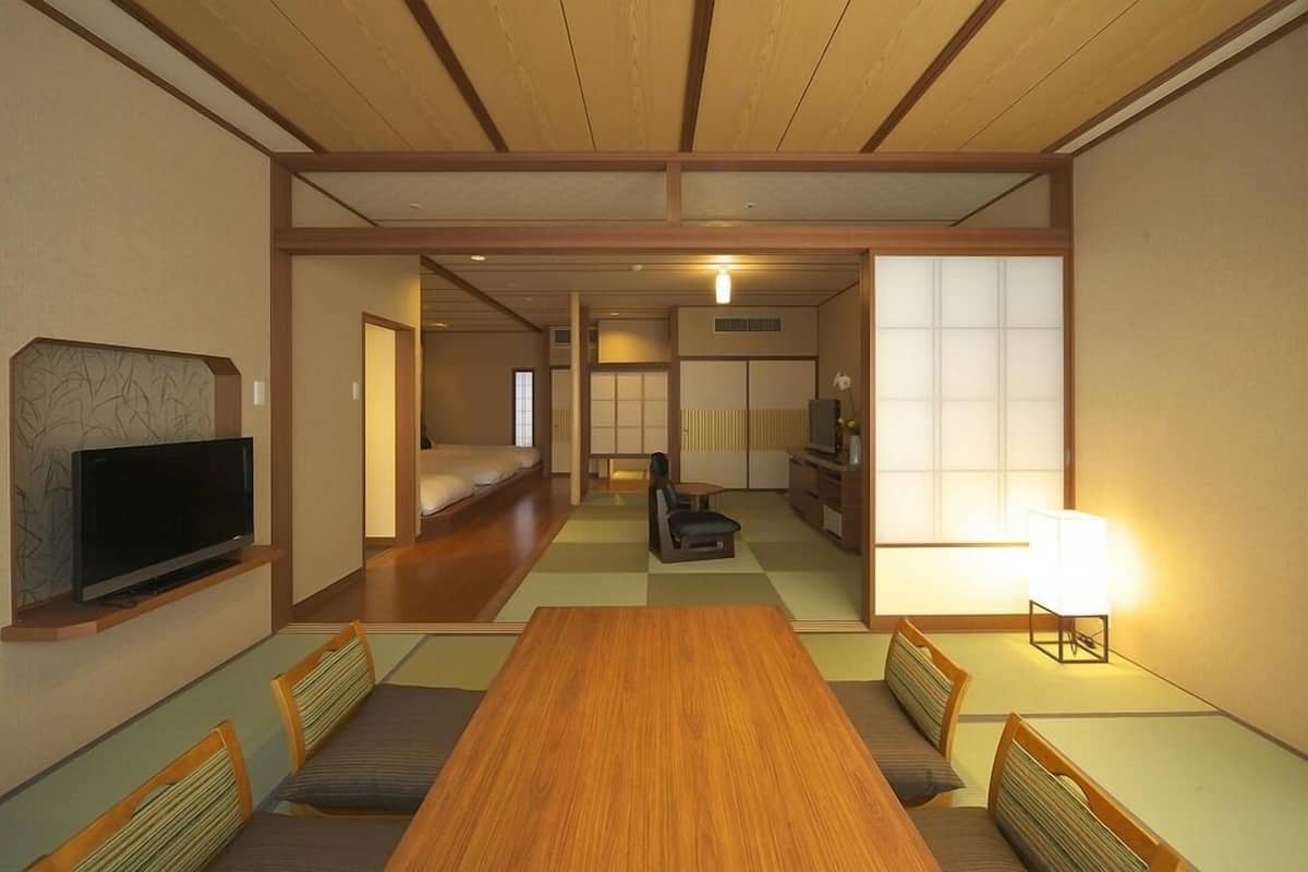 Una habitación tradicional japonesa con suelo de tatami, techo de madera bajo y puertas correderas.