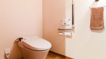 A modern bathroom with a toilet, a hand dryer, and a towel hanging on a rack.
