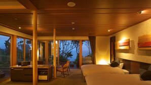 A modern hotel room with a large bed, a desk, and a chair. There is a view of the outdoors through large windows. - Hotel Bettei Umi To Mori (Choshi)