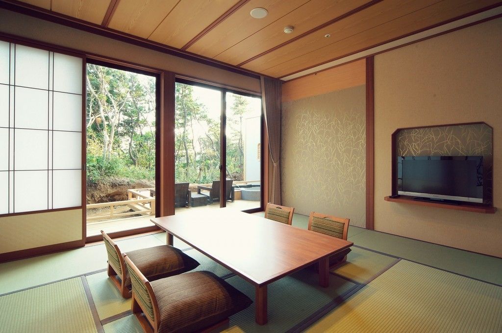 Une pièce de style japonais traditionnel, avec un sol recouvert de tatamis, une basse table en bois et des portes coulissantes donnant sur un espace extérieur.