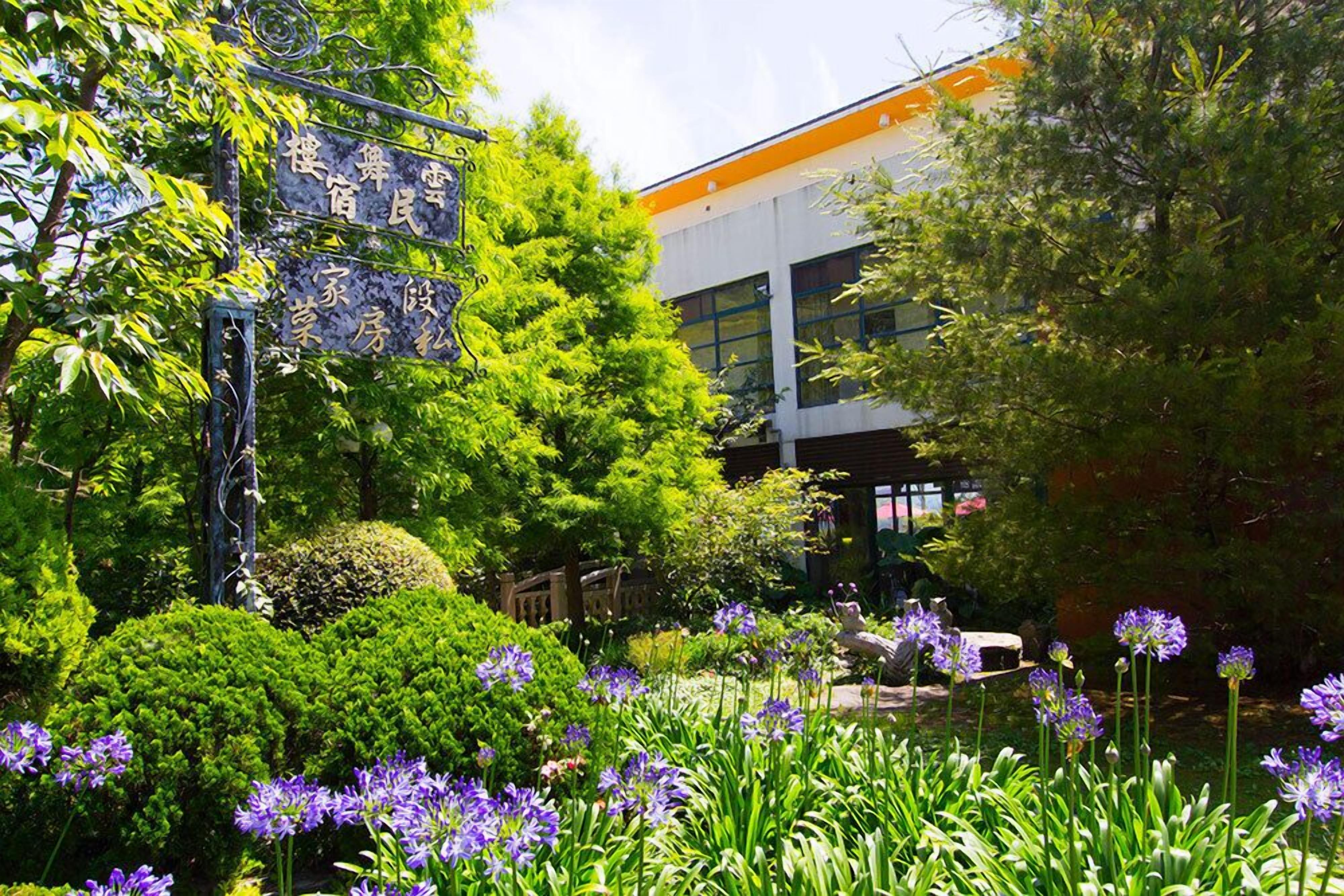 Ein Garten mit violetten Blüten und einem Gebäude im modernen Stil.