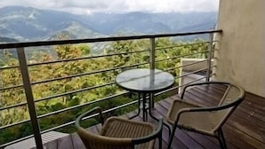 Un balcón con una mesa y sillas, con vistas a un paisaje montañoso.