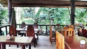 An outdoor dining area with wooden tables and chairs, surrounded by greenery. - Khao Sok Island Resort and Spa (Phanom)