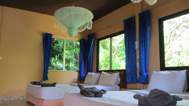 A room with two beds, a patterned floor, and large windows with blue curtains. - Khao Sok Island Resort and Spa (Phanom)
