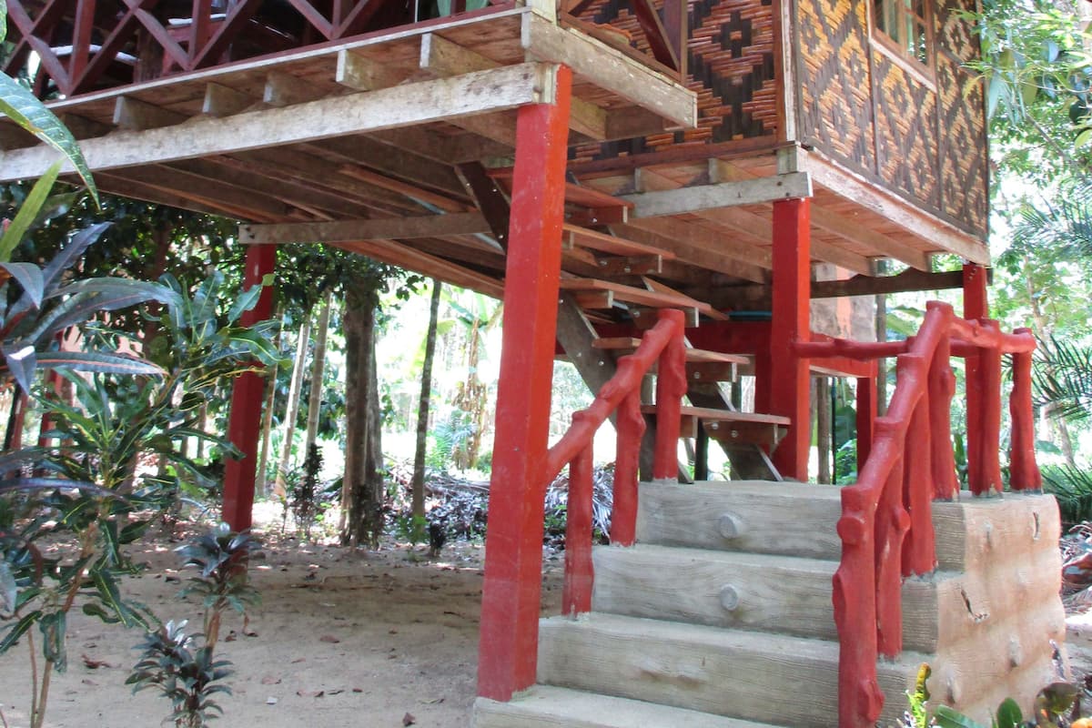Une structure traditionnelle en bois, dotée d’un balcon, de rampes rouges et de murs décorés de motifs.