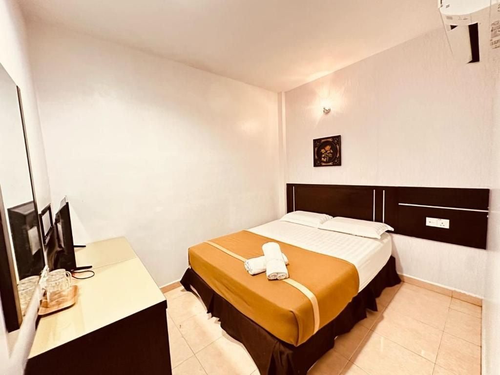 Ein Hotelzimmer mit einem Bett, einem Schreibtisch mit Computer und einer Wandleuchte.