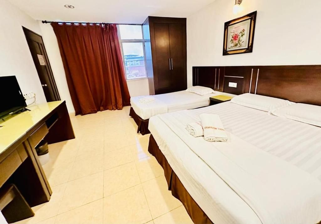 Habitación de hotel con dos camas, un escritorio, un armario y una ventana con cortinas.